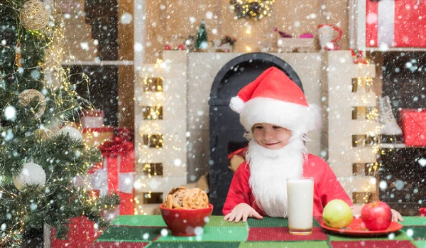눈 속의아이. 산타 클로스. 크리스마스 음식 과 음료. 산타 클로스가 진저브레드 케이크와 우유를 맛있게 먹고 있어. 산타 클로스가 유리에서 우유를 마시고 쿠키를 들고 있는 모습. — 스톡 사진
