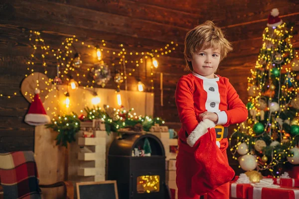 Glad liten leende pojke med julklappsstrumpor. Nyårskoncept. Glad unge som har kul med gåvan. — Stockfoto