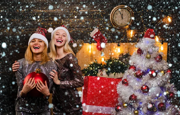 Девушки в снегу. Девушки в красной шляпе Санты держат подарок. Друзья Рождество. Концепция Рождества и Нового года. Чувственная женщина. Мода портрет модели две девушки в помещении с рождественской елкой . — стоковое фото