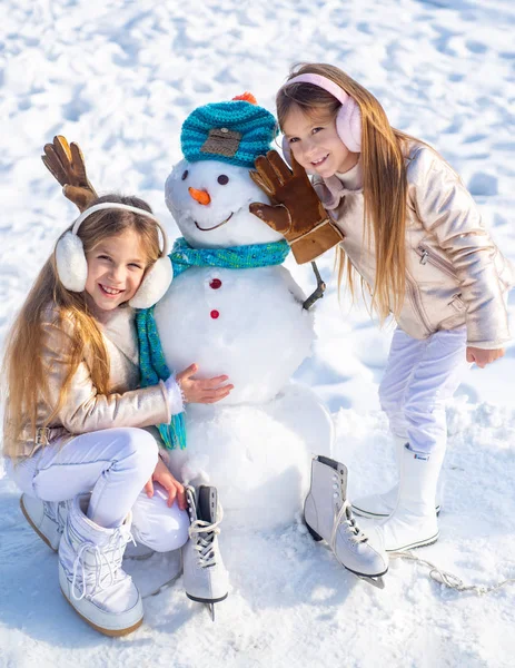 Enfants heureux jouant avec un bonhomme de neige lors d'une promenade hivernale enneigée. Joyeux hiver pour les enfants . — Photo