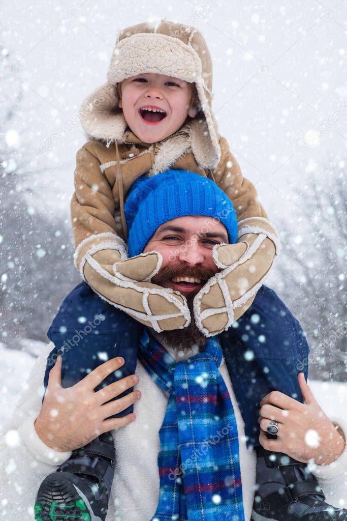 Daddy and boy smiling and hugging. Christmas holidays and winter new year with father and son. Winter scene on white snow background.