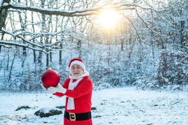 Noel kutlaması tatili. Mutlu Noeller ve mutlu yıllar konsepti. Kırmızı elbiseli Noel Baba Noel yolu boyunca yürüyor..