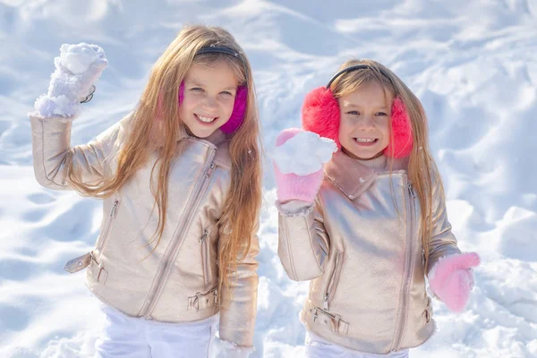 Porträtt av två små flickor leker med snö på vintern. Glad vintertid. Vinterbarn poserar och har roligt. Söta systrar som leker i snö. — Stockfoto
