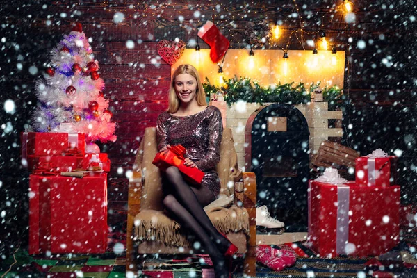 Dziewczyna w śniegu. Portret pięknej dziewczyny w stroju Mikołaja. Blondynka Mikołajowa trzyma pudełko na zabytkowej ścianie. Święta mody. Sexy Santa Clause kobieta w eleganckiej sukience. — Zdjęcie stockowe