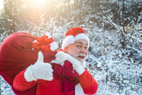 サンタの肖像画が閉じます。新年のクリスマスの概念。サンタクロースは白い自然の背景に贈り物の巨大な袋を引く. — ストック写真