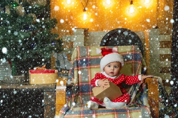 Niño en la nieve. Niño con un regalo de Navidad sobre fondo de madera. Niños de Navidad. Lindo niño está decorando el árbol de Navidad en el interior. Niños felices . —  Fotos de Stock