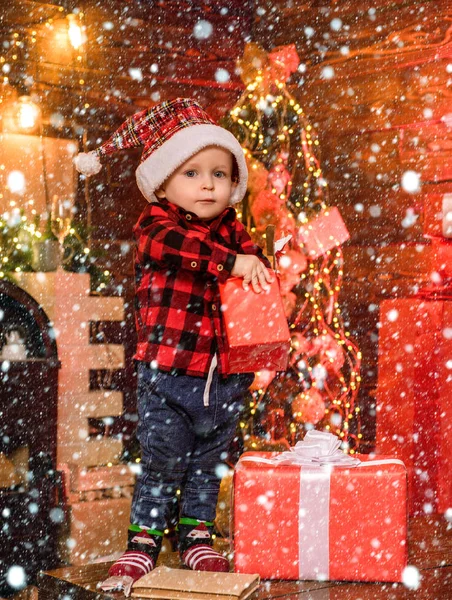 プレゼントを開く。素敵な赤ちゃんはクリスマスをお楽しみください。サンタ少年の小さな子供は、自宅でクリスマスを祝います。子供の頃の思い出男の子かわいい子供陽気な気分クリスマスプレゼント。中に何があるか。陽気で明るいクリスマス — ストック写真