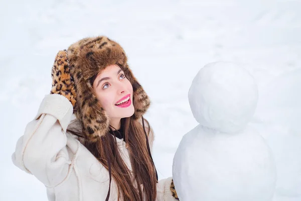 Радісна молода жінка, Веселощі з сніговиком у Зимовому парку. Кумедні сніговики. Щаслива усмішка робить сніговика сонячним зимовим днем.. — стокове фото