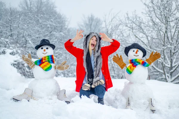 Boldog lány téli portré. Boldog hóember áll a téli karácsonyi táj. Téli nő a fagyos téli parkban. — Stock Fotó