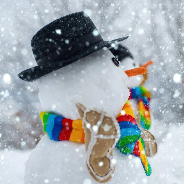 Boldog hóember áll a téli karácsonyi táj. A hóember szőrmekalapot és sálat visel. Boldog karácsonyt és boldog új évet! Hóember a hóban. — Stock Fotó