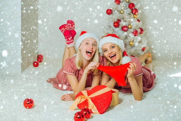 Κορίτσια στο χιόνι. Οι καλύτερες φίλες των Χριστουγέννων. Σέξι κορίτσια που φοράνε ρούχα του Άη Βασίλη. Χαρούμενοι φίλοι γιορτάζουν τα Χριστούγεννα στο σπίτι. Σέξι κόκκινα εσώρουχα για το νέο έτος. Είχα μια τρελή μέρα με μια φίλη.. — Φωτογραφία Αρχείου