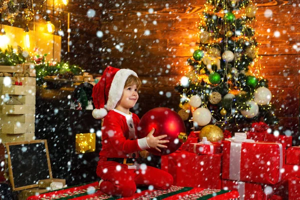 素敵な赤ちゃんはクリスマスをお楽しみください。子供の頃の記憶サンタ少年の子供は自宅でクリスマスを祝います。家族の休日男の子はクリスマスツリーの近くで遊ぶ。新年のカウントダウン。陽気で明るいクリスマス — ストック写真