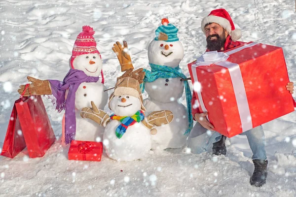 Ember és hóember a hóban. Ajándékokat hoztam. Boldog téli hóember családot. Az anya hóasszony, az apa hóember és a gyerek boldog karácsonyt és boldog új évet kíván. Aranyos hóember egy havas faluban.. — Stock Fotó