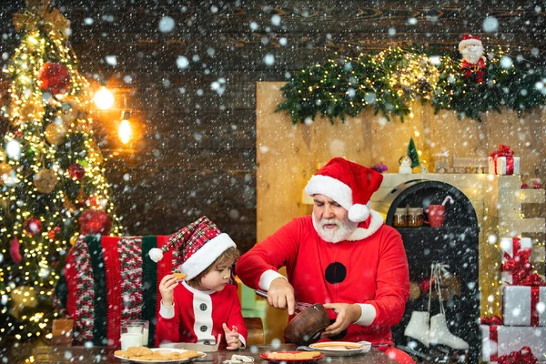 Santa helper. Happy father and son in Santa hat with cookies have a Christmas. Christmas interior. Happy new year. Christmas Celebration holiday.