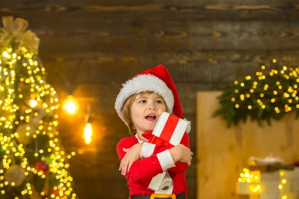 Criança com dom. Criança feliz decorar árvore de Natal. Interior de Natal. Conceito de ano novo. Criança menino feliz com presente ou caixa de presente dentro de casa . — Fotografia de Stock