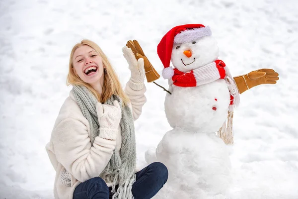 Érzéki téli lány pózol és jól érzi magát. Téli waman hóemberrel a háttérben. Téli portré. — Stock Fotó