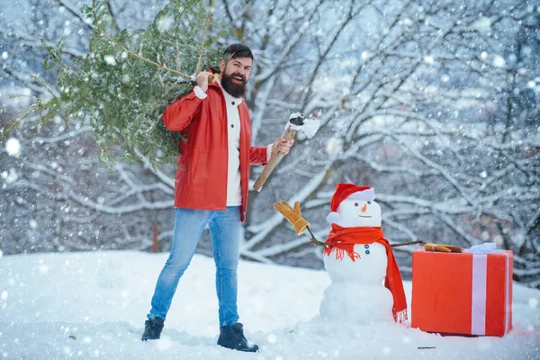 Mann im Schnee. Der Mann wird einen Weihnachtsbaum fällen. Wintergefühle. bärtiger Mann mit frisch gefälltem Weihnachtsbaum im Wald. Frohe Winterzeit. Frohe Weihnachten und frohe Feiertage. — Stockfoto