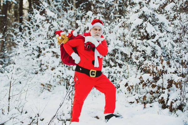 Ευτυχισμένο το νέο έτος. Άγιος Βασίλης τράβηγμα τεράστια τσάντα των δώρων σε λευκό φόντο της φύσης. Ο Άγιος Βασίλης στο χειμερινό χωράφι. Καλά Χριστούγεννα και Ευτυχισμένο το νέο έτος. — Φωτογραφία Αρχείου
