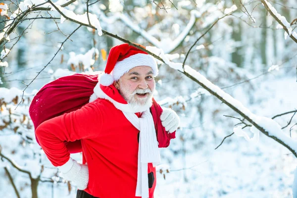 サンタは赤いスーツでクリスマスへの道を歩く。大きな袋でサンタクロース。サンタクロースには外からの贈り物が付属しています. — ストック写真