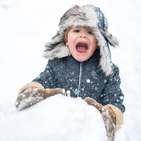 Enfant dans la neige. Joyeux enfant jouant avec un bonhomme de neige lors d'une promenade hivernale enneigée. Joyeux hiver. Des gens dans la neige. Profiter de la nature hivernale . — Photo