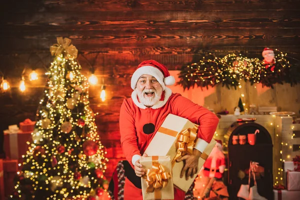 Ein glücklicher Weihnachtsmann in Winterkleidung denkt an Weihnachten in der Nähe des Weihnachtsbaums. Porträt eines reifen Weihnachtsmannes. Neujahrskonzept. Heimelige Weihnachtsstimmung. — Stockfoto