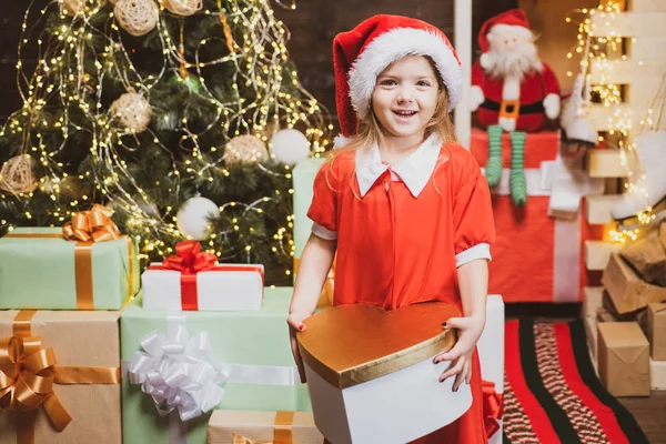 Χριστουγεννιάτικα στολίδια. Τα παιδιά απολαμβάνουν τις διακοπές. Χριστουγεννιάτικο παιδί που κρατάει ένα κόκκινο κουτί δώρου. Ευτυχισμένο μικρό κορίτσι με δώρο ή κουτί δώρου σε εσωτερικούς χώρους — Φωτογραφία Αρχείου