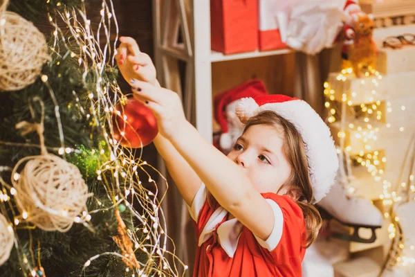 Рождественская игрушка - девушка украшает елку. Рождественский ребенок украшает елку безделушками. — стоковое фото