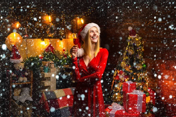 Jonge Santa vrouw met een glas wedow champagne viert Kerstmis binnen in een prachtig ingerichte kamer. Vrolijk kerstfeest. Binnenshuis. Winkelverkoop. Nieuwjaar. Cadeaudienst. — Stockfoto