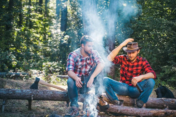 Happy friends on a camping trip relaxing by campfire. Friends relaxing near campfire after day hiking or gathering mushrooms. Friendship and leisure concept. — Stock Photo, Image