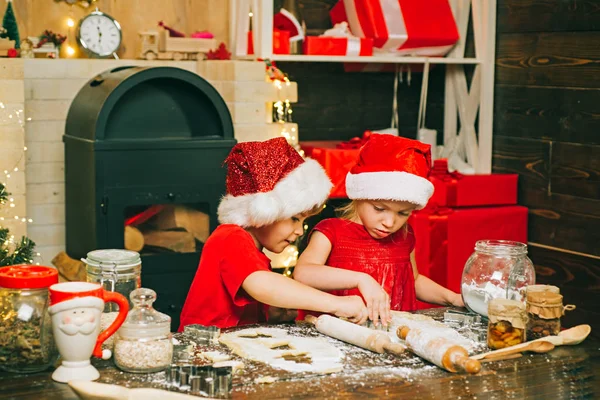 Frohe Weihnachten. Weihnachtliches Essen und Trinken. Weihnachtsmänner backen Plätzchen. Lustige Kinder bereiten in der Küche den Teig mit Mehl zu. — Stockfoto