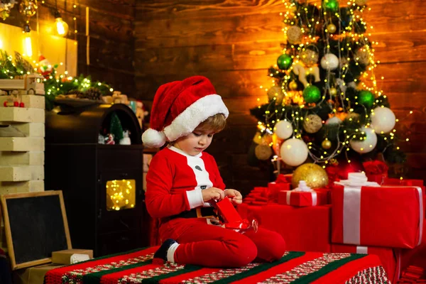 Wish you merry Christmas. Little Santa Claus gifting gift. Winter Christmas emotion. Home Christmas atmosphere.