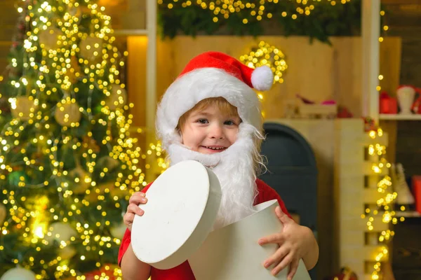 Glückliches kleines Kind mit Geschenk oder Geschenkbox drinnen. Weihnachtliches Kinderporträt. Kinder haben Spaß mit Geschenken. Geschenkemotionen. — Stockfoto