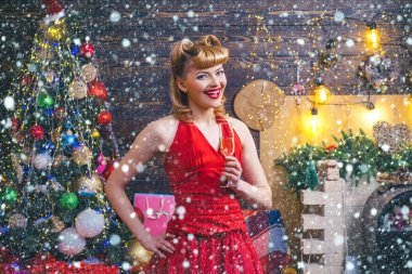 Akşam kırmızı elbisesi içinde gülen bir kadın ve bir bardak köpüklü şarap Noel ağacı arka planında. Moda, güzellik, makyaj ve Noel için saç stili..