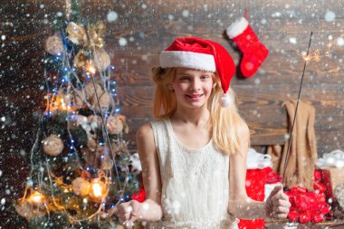 Çocuklar içeride Noel ağacının yanında eğleniyorlar. Çocuk hediyesi. Noel kartı. Mutlu küçük kızın portresi Noel ağacının yanındaki oyuncak topuna bakıyor..