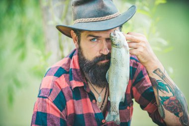 Sakallı adam balık yakalıyor. Başarılı bir yakalayış. Büyük balık avı. Hafta sonları balık tutmak içindir. İyi balık avları. Suyun yanında mutlu bir balıkçı. Yakışıklı adam dinleniyor..