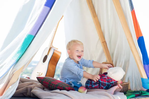 Niño feliz parado en la hierba en el soleado día de verano. Niño al aire libre en la naturaleza en el camping. Niño feliz jugando con juguete en verano . —  Fotos de Stock