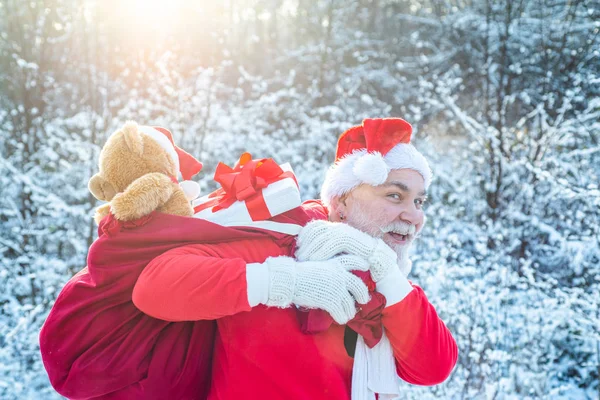 サンタクロースは雪景色の贈り物の袋を持って冬の森に来ています。メリークリスマスと幸せな休日。サンタポートレートを閉じます. — ストック写真