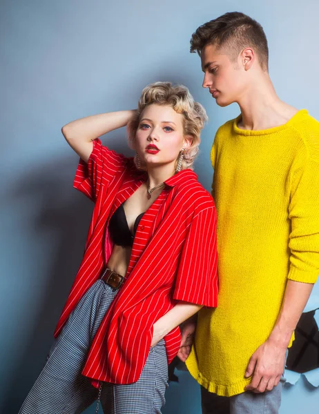 Prachtige vrouw met in rood shirt poseren met knappe brunette man in gele trui. Fashion portret mooi sexy paar. Commercieel ontwerp. Jongeren in jeans op een donkere achtergrond. Mode. — Stockfoto