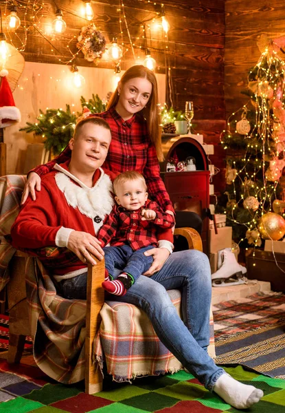 Noel ağacının yanında mutlu bir aile. Aile amaçları. Bebek bir Noel hediyesi açıyor. Arka planda öpüşen ebeveynler çok hoştu. Baba, anne ve çocuğu ellerinde.. — Stok fotoğraf