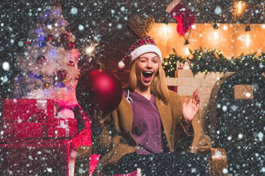 Noel ve Noel hediyeleri aşkına. Kadın Noel 'i. Göz kırp. Çılgın komik surat. Genç kadın göz kırpıyor. Komik somurtkan. Noel kadınının elinde bomba var. Yaratıcı patlama. Bomba duyguları.