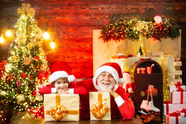 Hediyelerle dolu Noel Baba çocuk. Noel ve Yeni Yıl posterleri için. Sevimli çocuk ve büyükbaba evde Noel Baba 'yı oynuyor..