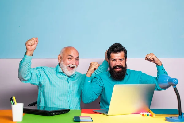 Freelance work style and business meeting. Two senior business colleagues at meeting in office. Two male senior man employees consulting with laptop in office.