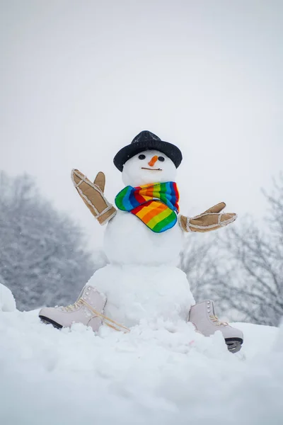 Muñeco de nieve con bufanda y sombrero. Feliz muñeco de nieve divertido en la nieve. Fondo de invierno con copos de nieve y muñeco de nieve. Feliz muñeco de nieve de pie en invierno Navidad paisaje —  Fotos de Stock