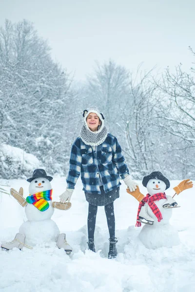 Téli jelenet boldog emberek fehér hó háttér. Téli nap. Téli női ruhák. Aranyos hóember egy havas faluban. Üdvözlő hóember. — Stock Fotó