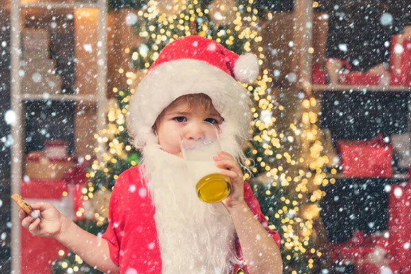サンタクロースはクリスマスの前夜に彼のために残されたクッキーとミルクを楽しんでいます。クリスマスライトの背景に対してサンタのためのミルクとジンジャーブレッドクッキー。サンタクロースのミルクとクッキー. — ストック写真