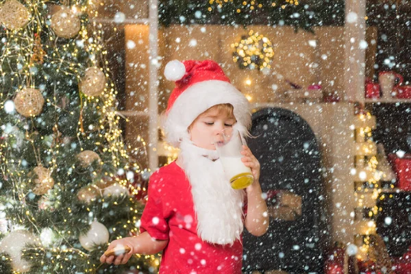 クリスマスカードをサンタクロースの肖像ガラスから牛乳を飲み、クッキーを持っています。サンタクロースはクリスマスクッキーとミルクをクリスマスツリーの背景に持っている. — ストック写真