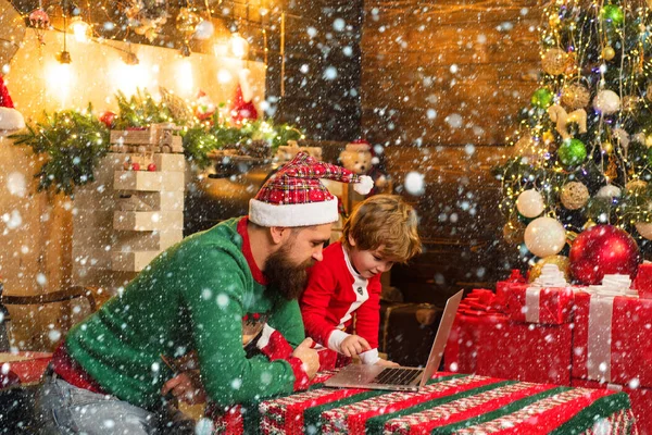 Bonito menino e papai com laptop ou computador perto da árvore de Natal . — Fotografia de Stock