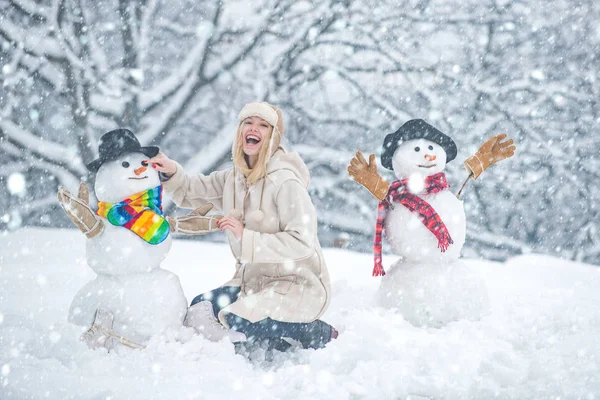 Vicces hóemberek. Boldog mosolygós lány, hogy hóember a napos téli napon. Emberek a hóban. Hóember. Szépség Téli lány hóemberrel a fagyos téli parkban. — Stock Fotó