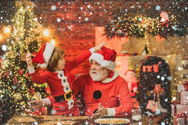 Ajudante de Pai Natal. Kid neto e avô em Santa Hat Writing Wish List - fundo luzes sem foco. Criança escrever carta para Santa. — Fotografia de Stock