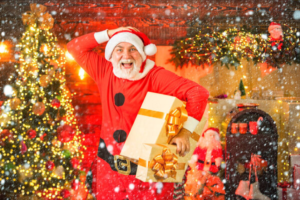 Рождественская подготовка - Санта-дедушка празднует Новый год. Забавный Санта держит рождественский подарок.